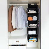 Closet with hanging clothes and a black vertical organizer.