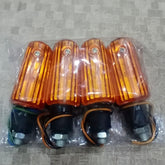 Four orange motorcycle turn signals in packaging on a gray textured surface