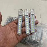 Three LED light bars held in a hand with a tiled floor background