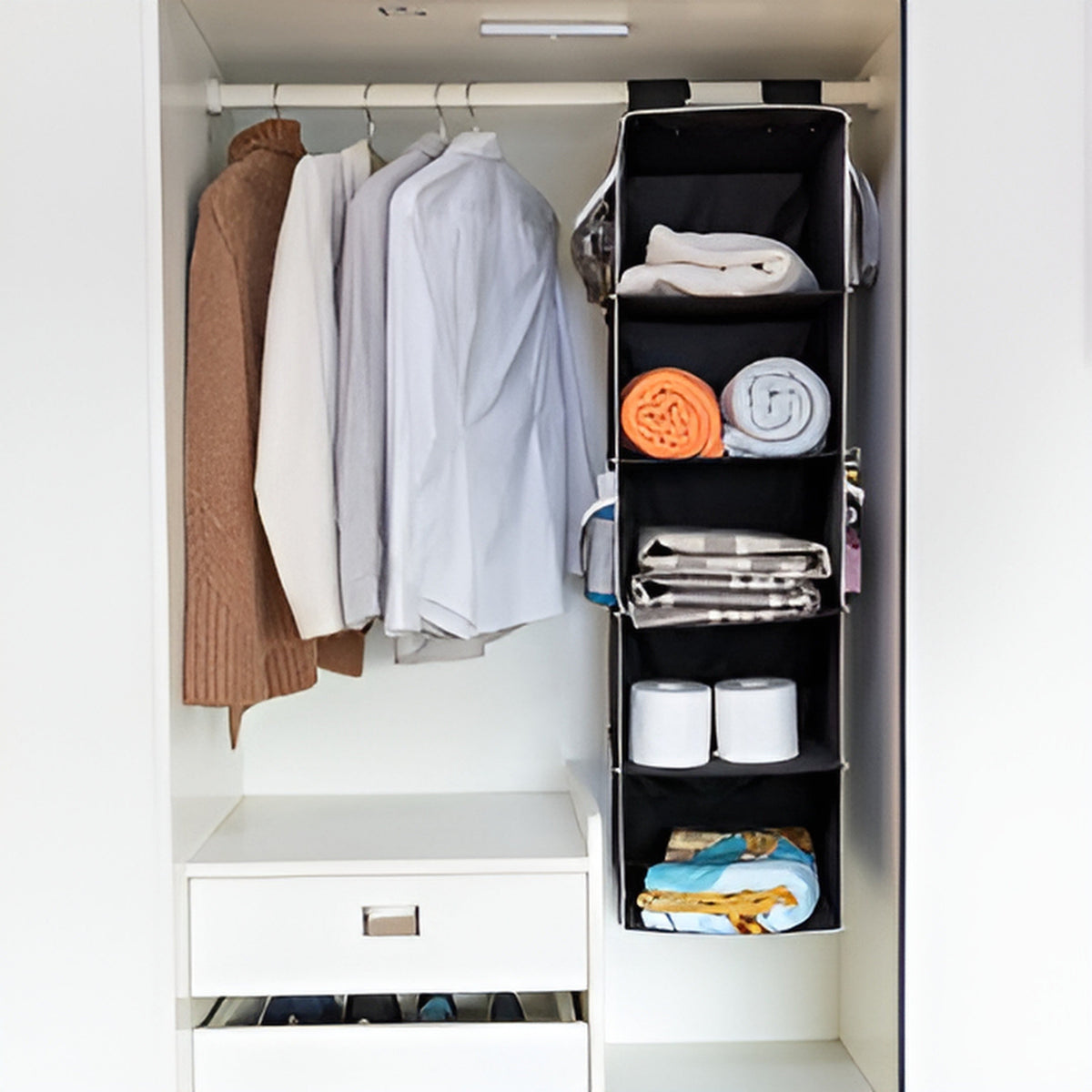 Closet with hanging clothes and a black vertical organizer.