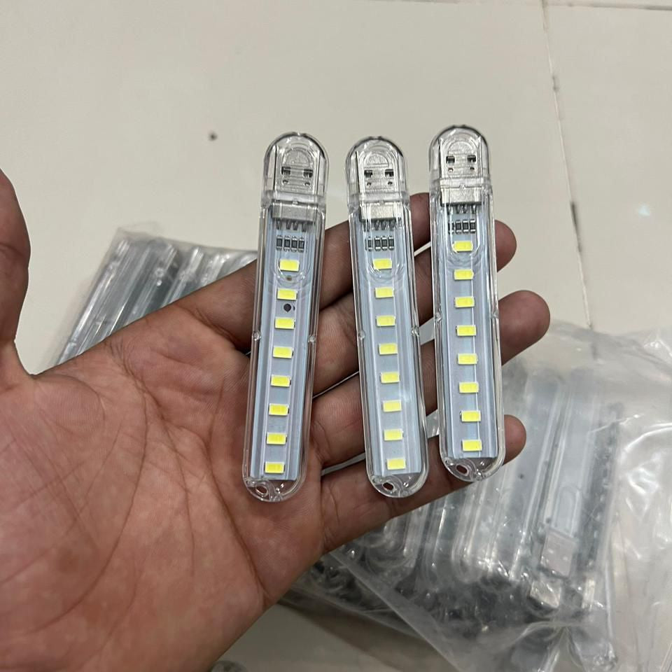 Three LED light bars held in a hand with a tiled floor background