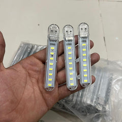 Three LED light bars held in a hand with a tiled floor background